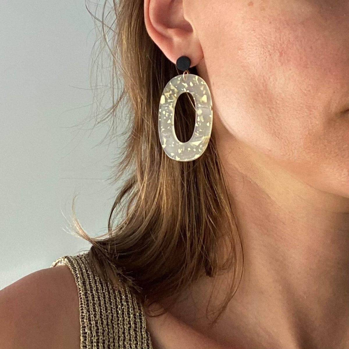 Boucles d'oreille paillettes or et Lego mettant en avant une élégante pièce ovale en acétate.