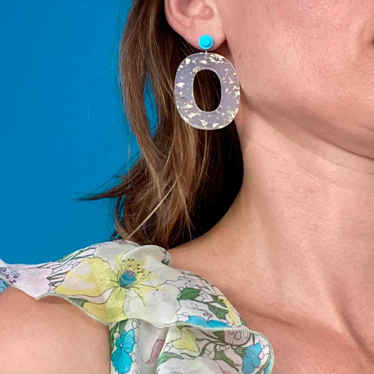 Boucles d'oreille paillettes or et Lego portées avec une tenue estivale colorée, mettant en avant leur élégance.