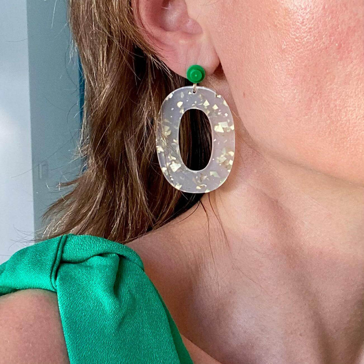Boucles d'oreille paillettes or et Lego avec une pièce ovale en acétate blanc et une brique Lego colorée.