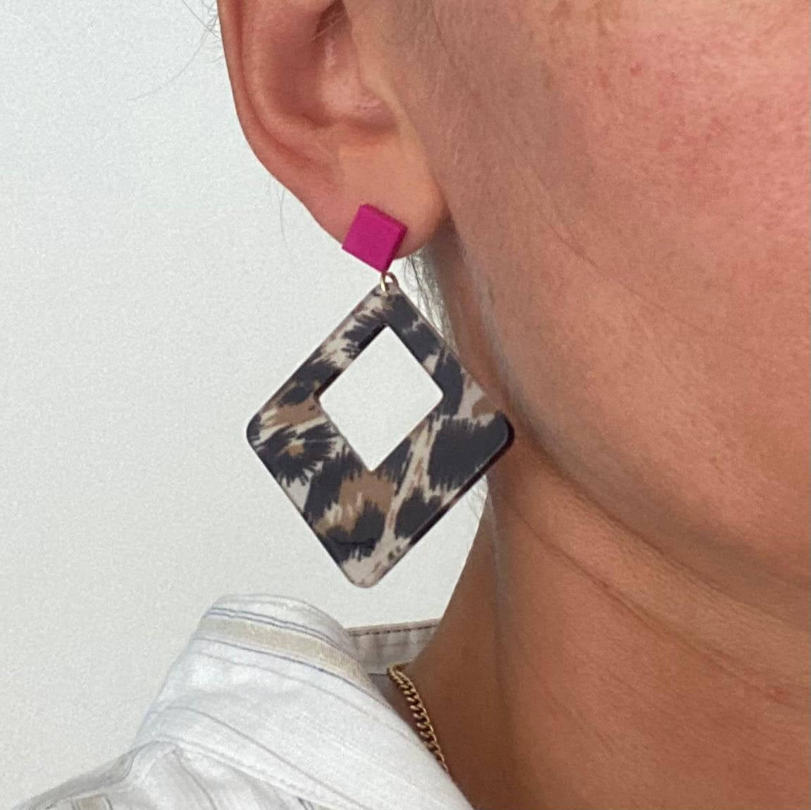 Boucles d'oreilles Léopard en acétate carré avec détail en rose portée par une personne.