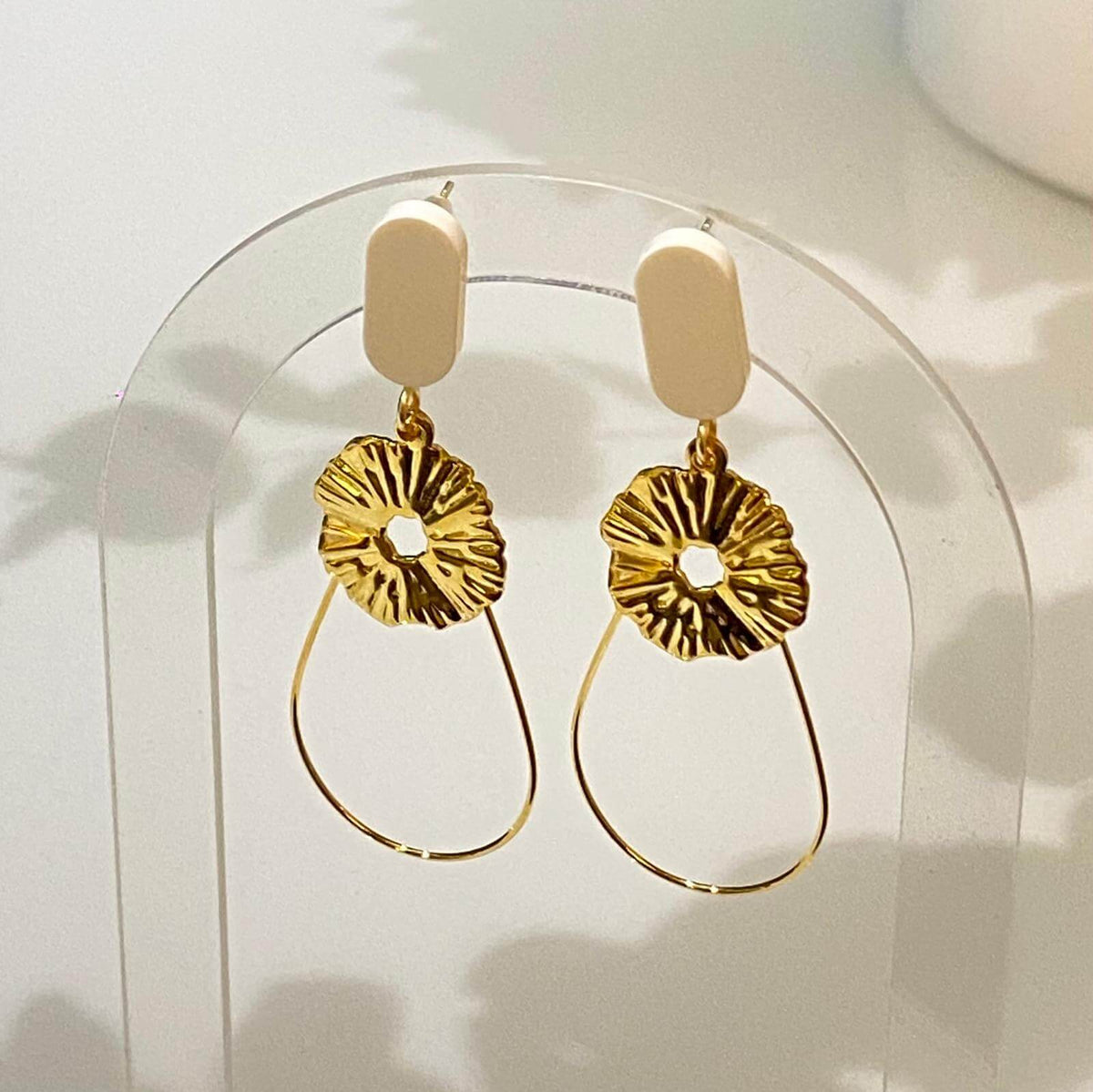 Boucles d'oreilles chic avec un Lego lisse et subtil auquel est suspendu une goutte en fil doré et un soleil. Un bijou avec un Lego pour un effet raffiné aux teintes peau et rosées