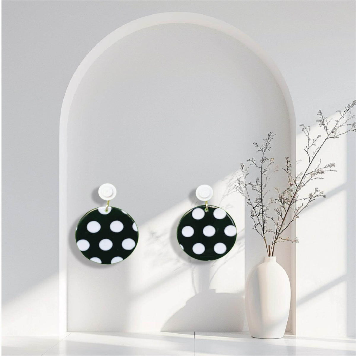 Boucles d'oreilles à pois noirs et blancs accrochées à l'oreille par une brique de Lego ronde dans un décors minimaliste