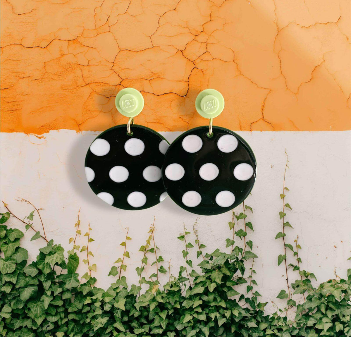 Boucles d'oreilles à pois noirs et blancs accrochées à l'oreille par une brique de Lego ronde vert citron vert