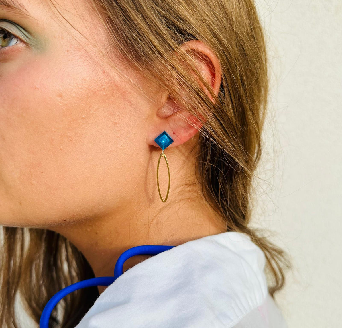Boucle d'oreilles pendante avec un oval en laiton doré suspendue à une brique de Lego 1x1 plate bleu foncé transparent, esprit saphir. Elle se coordonne parfaitement avec les pulls, écharpes, robes bleu foncé ou bleu roi. Magnifique sur les femmes aux yeux bleus.