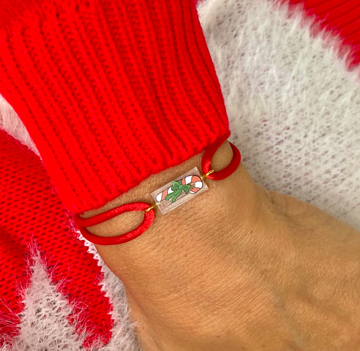 Bracelet spécial Noël avec un sucre d'orge imprimé sur une brique de Lego authentique. Le bracelet se règle avec un cordon rouge soyeux ajustable coulissant facilement.