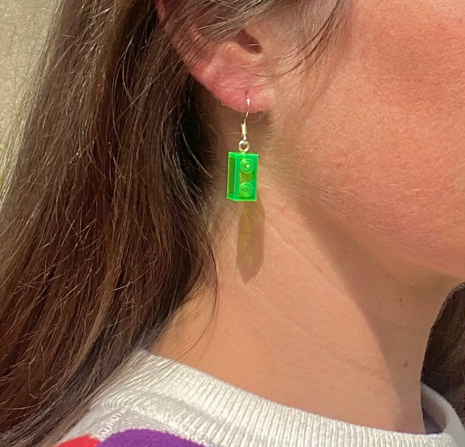 Boucles d'oreilles pendantes argentées avec une brique Lego 1x2 verte, ajoutant une touche de couleur à votre look.