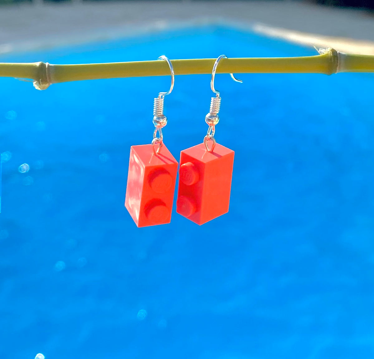 Boucles d'oreilles pendantes en brique Lego rose corail, créées pour ajouter une touche colorée et fun à votre look.