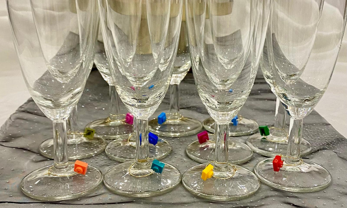 Marque-verres en acier inox sur flûtes à champagne, ajoutant une touche de Lego pour vos soirées conviviales.