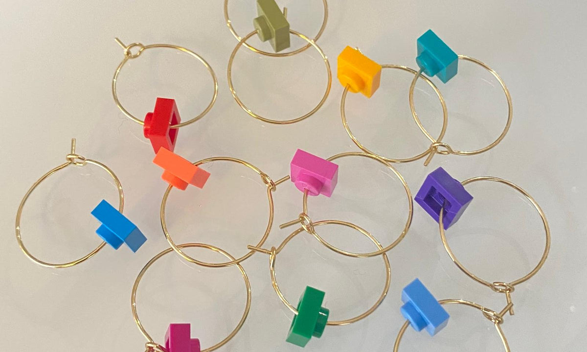 Marque-verres en acier inox avec des accessoires colorés en forme de brique Lego pour soirées entre amis.