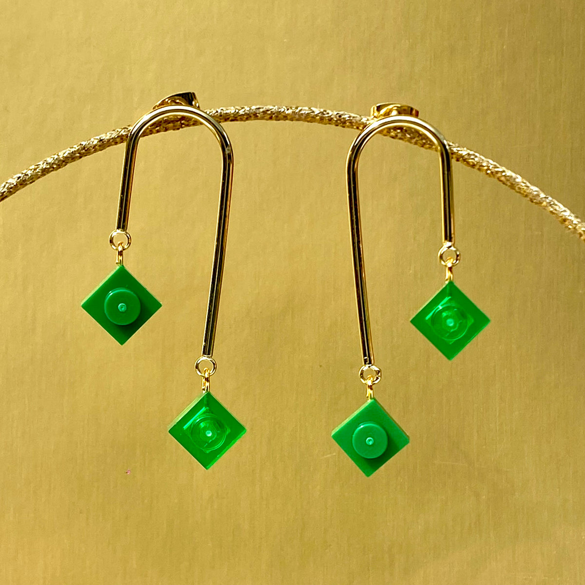 Boucles d'oreilles pendantes avec brique de lego vertes opaques et translucides, design graphique et asymétrique, inspirées de l'art déco.