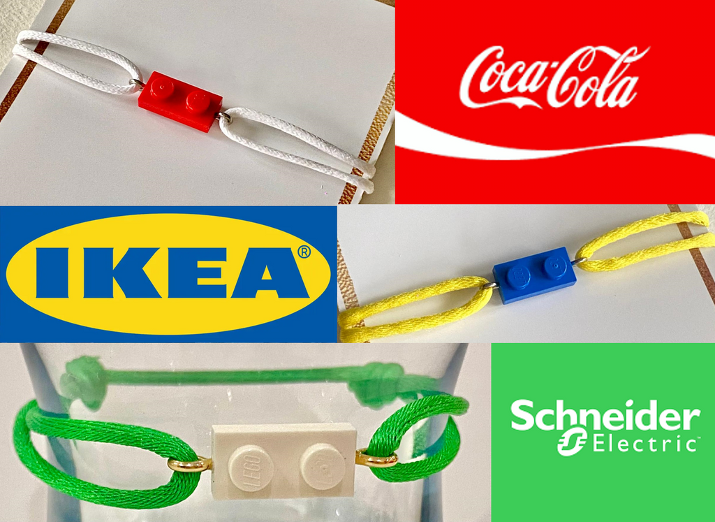 Idée de cadeau de team building : le bracelet bicolore de Brique d'Oreille avec une brique de Lego et un cordon ajustable, aux couleurs de marques. En exemple: Ikea en bleu et jaune, Coca-Cola, en rouge et blanc, et Schneider Electric en vert et blanc
