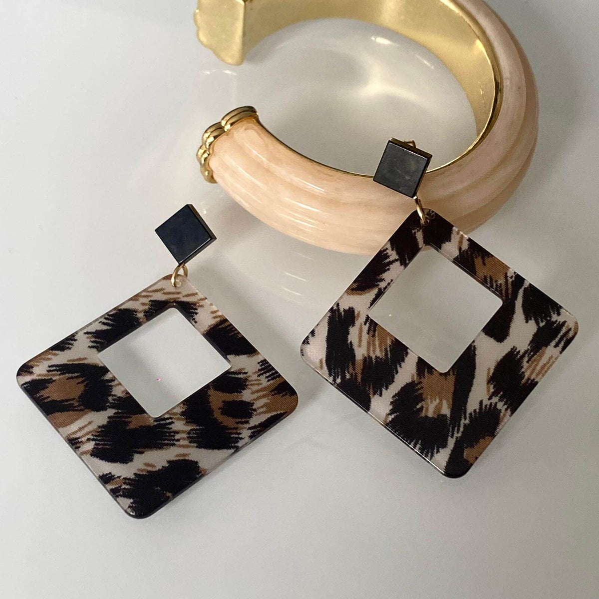 Boucles d'oreilles Léopard en acétate carrées élégantes avec un bracelet doré.