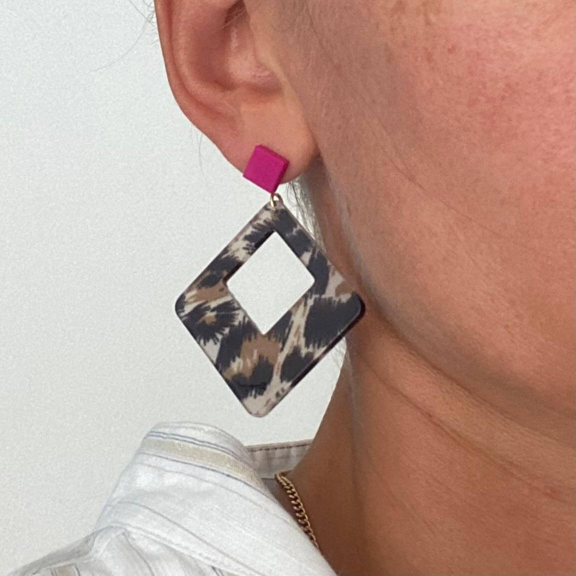 Boucles d'oreilles Léopard en acétate carré avec détail en rose portée par une personne.
