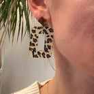 Boucles d'oreilles pendantes léopard et mini Lego portées, tendance et colorées, avec un style décalé.