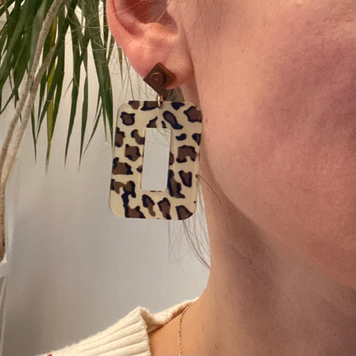 Boucles d'oreilles pendantes léopard et mini Lego portées, tendance et colorées, avec un style décalé.