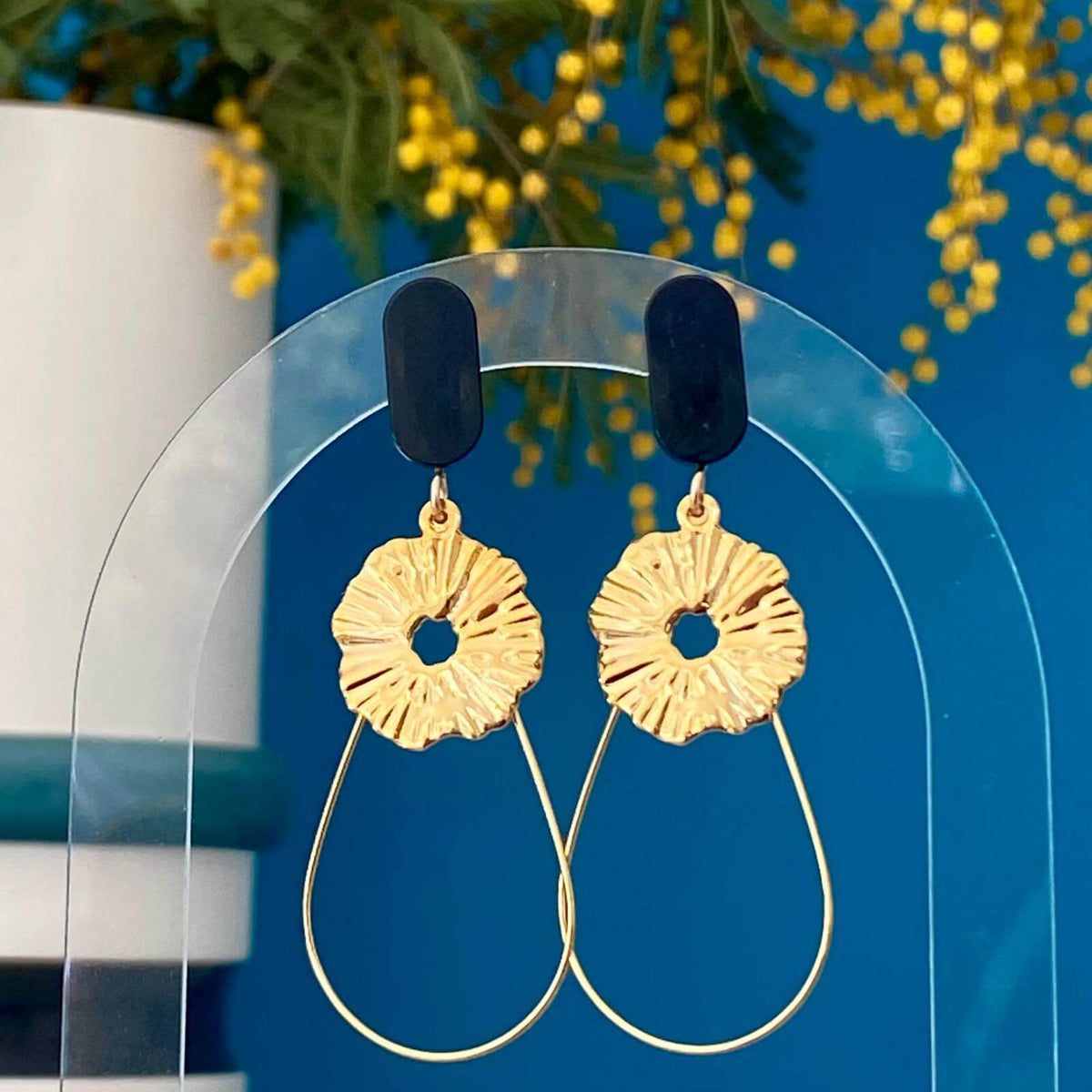 Boucles d'oreilles chic avec un Lego lisse et subtil auquel est suspendu une goutte en fil doré et un soleil. Un bijou avec un Lego noir pour un effet raffiné et intemporel