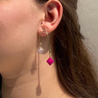 Boucles d'oreilles pendantes en or avec briques de Lego rose fuschia et transparente, style art déco, asymétriques et graphiques.