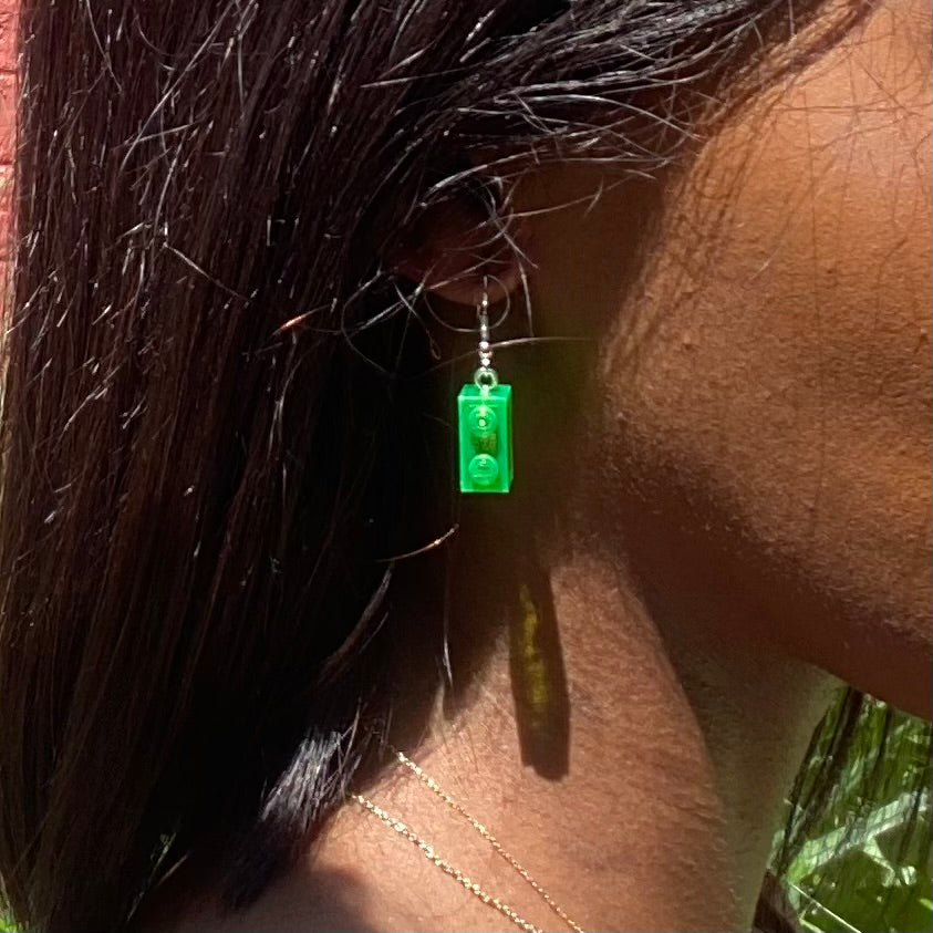 Boucles d'oreilles pendantes vertes en Lego, ajoutant une touche fun à votre look, avec une brique de 1x2 cm.
