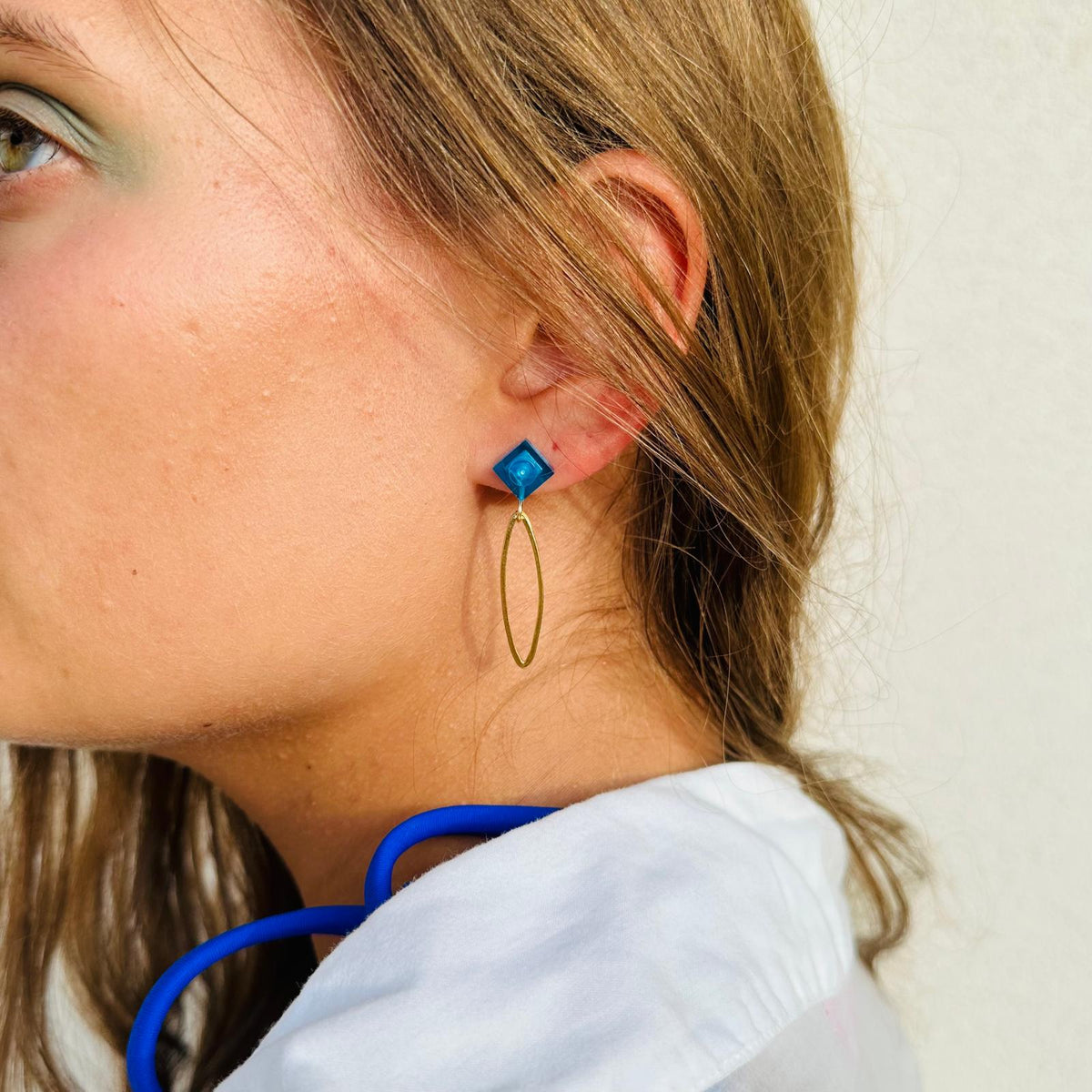 Boucle d'oreilles pendante avec un oval en laiton doré suspendue à une brique de Lego 1x1 plate bleu foncé transparent, esprit saphir. Elle se coordonne parfaitement avec les pulls, écharpes, robes bleu foncé ou bleu roi. Magnifique sur les femmes aux yeux bleus.