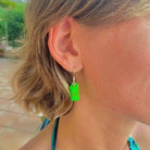 Boucles d'oreilles pendantes avec une brique Lego verte translucide effet fluo, la touche de couleur ludique pour un look original et unique.