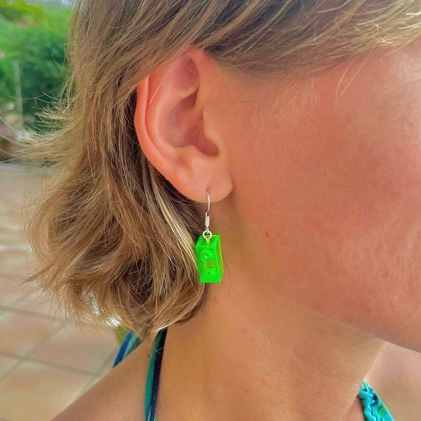 Boucles d'oreilles pendantes avec une brique Lego verte translucide effet fluo, la touche de couleur ludique pour un look original et unique.