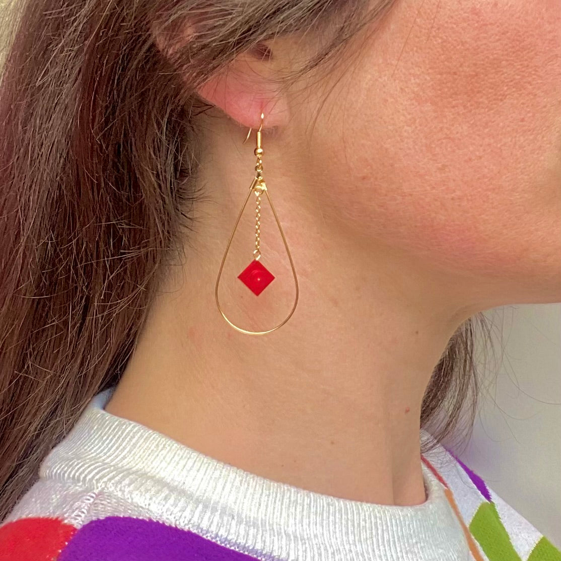 Boucles d'oreilles pendantes colorées en forme de goutte, très élégantes et raffinées grâce à la goutte en laiton doré à l'or fin très fine et légère et la petite chainette au milieu à laquelle est suspendue une brique de Lego rouge translucide effet rubis
