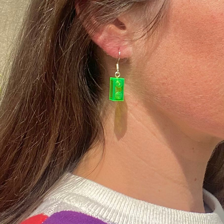 Boucles d'oreilles pendantes argentées avec une brique Lego 1x2 verte, ajoutant une touche de couleur à votre look.