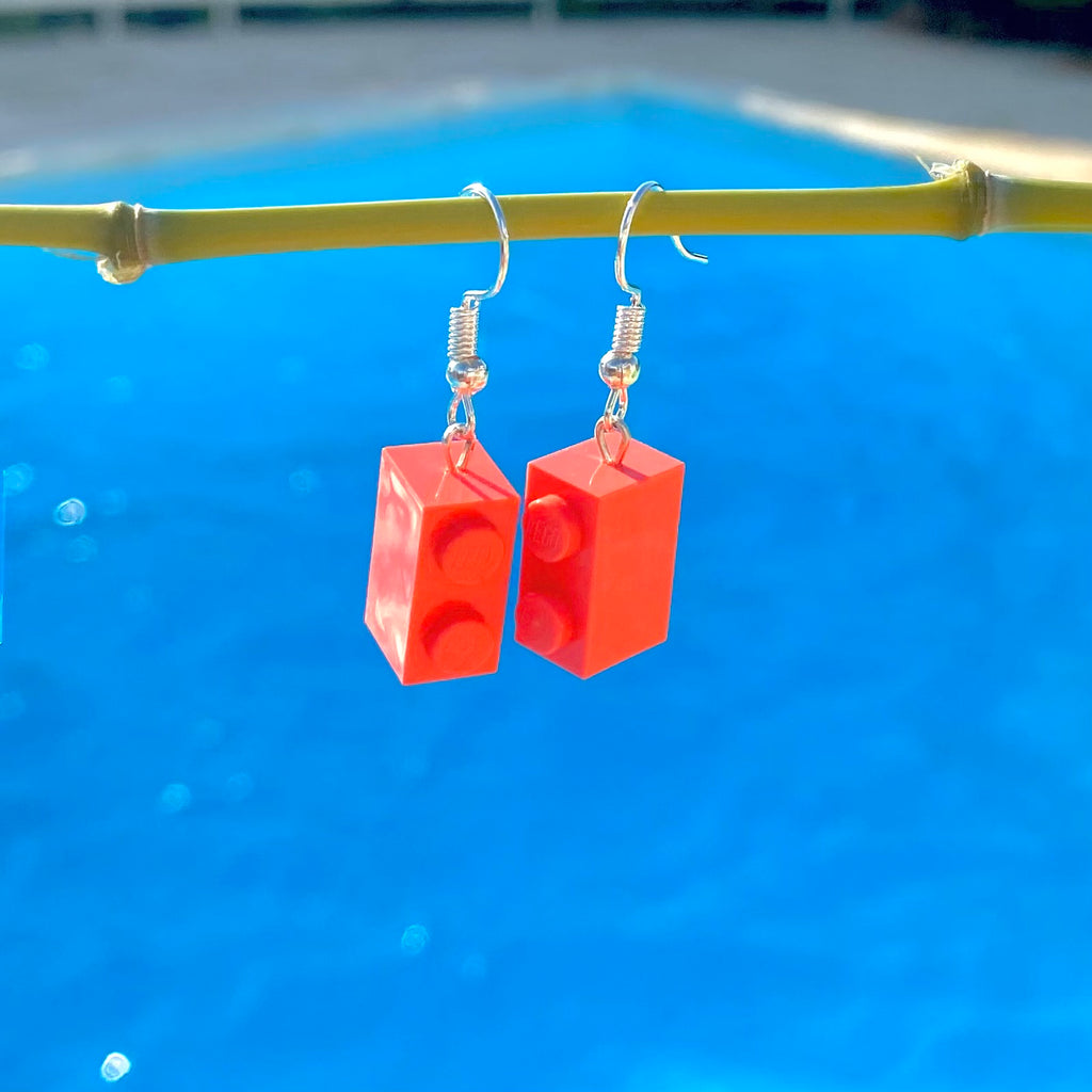 Boucles d'oreilles pendantes en brique Lego rose corail, créées pour ajouter une touche colorée et fun à votre look.