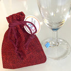 Marque-verres en acier inox avec un sachet rouge, idéal pour soirées nombreuses et bijoux pour les verres à pieds.