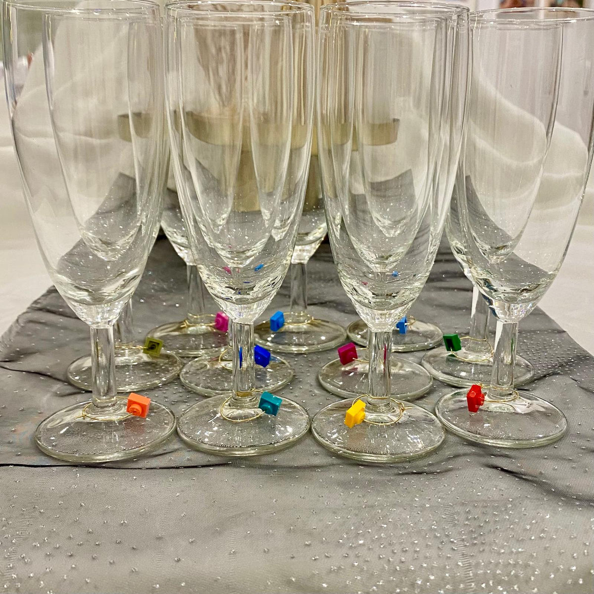 Marque-verres en acier inox sur flûtes à champagne, ajoutant une touche de Lego pour vos soirées conviviales.