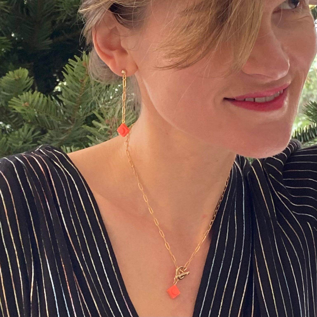 Boucles d'oreilles pendantes dorées avec brique Lego® colorée corail sur modèle, style original et léger.