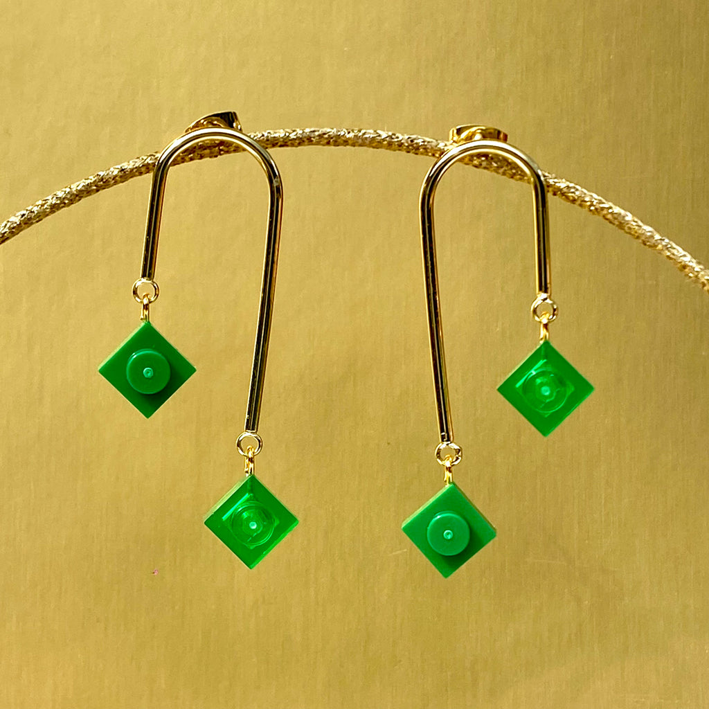 Boucles d'oreilles pendantes avec brique de lego vertes opaques et translucides, design graphique et asymétrique, inspirées de l'art déco.